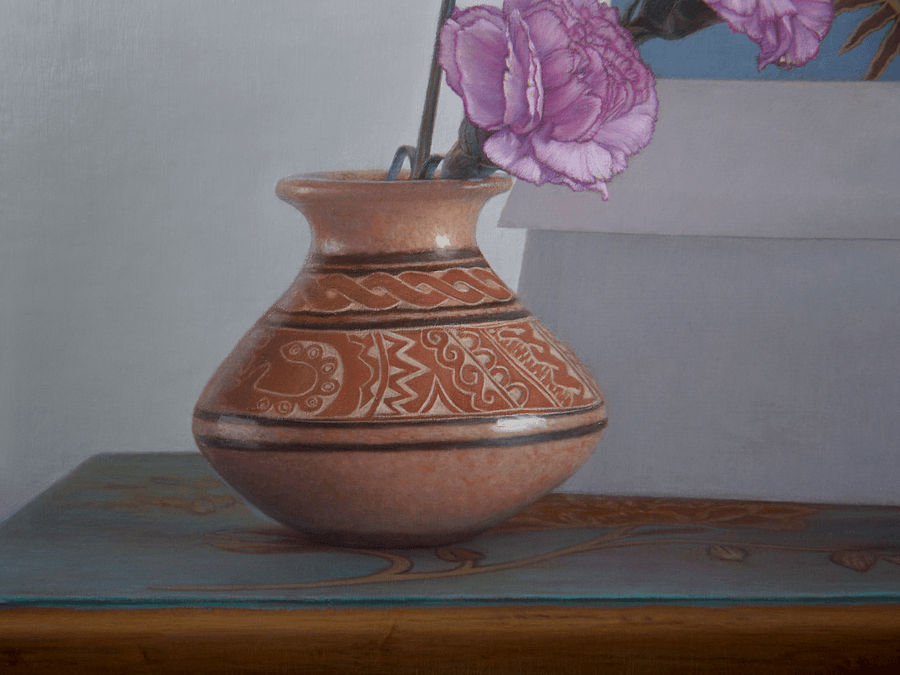 A detailed close-up from the oil painting 'Blue Table and Vase.' This view focuses on the glazed vase and the top of the blue table, highlighting the subtle carving  and design in the clay, and the painted plant motif on the blue table top. The detail showcases the fine brushwork on the painted wood and the realistic glints of light on the earth coloured vase. Oil painting by John Hansen.