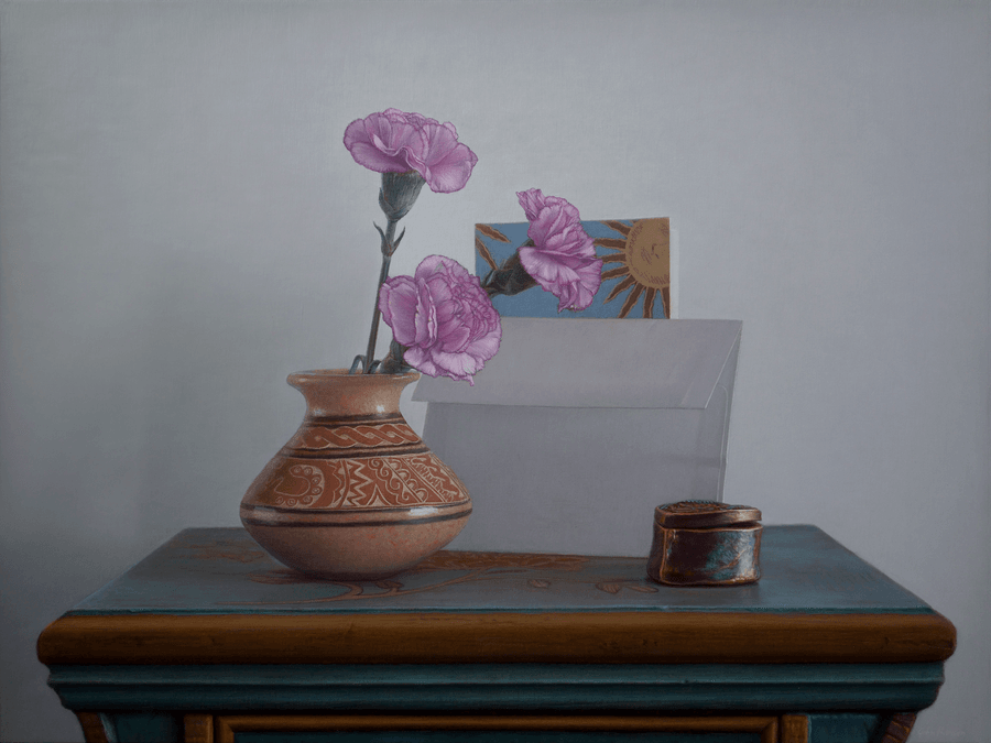 A realist oil painting titled 'Blue Table and Vase,' measuring 12 inches by 16 inches. A bright, sky-blue wooden side table with a single drawer and painted design accents stands against a soft grey, neutral wall. Resting on the table is a red terracotta vase containing three delicate pink carnations, a greeting card with an envelop, and a heart shaped container. The lighting is soft and directional from the right, casting a gentle shadow on the wall and creating textural reflections on the vase and the reflective blue surface of the table. Oil painting by John Hansen.
