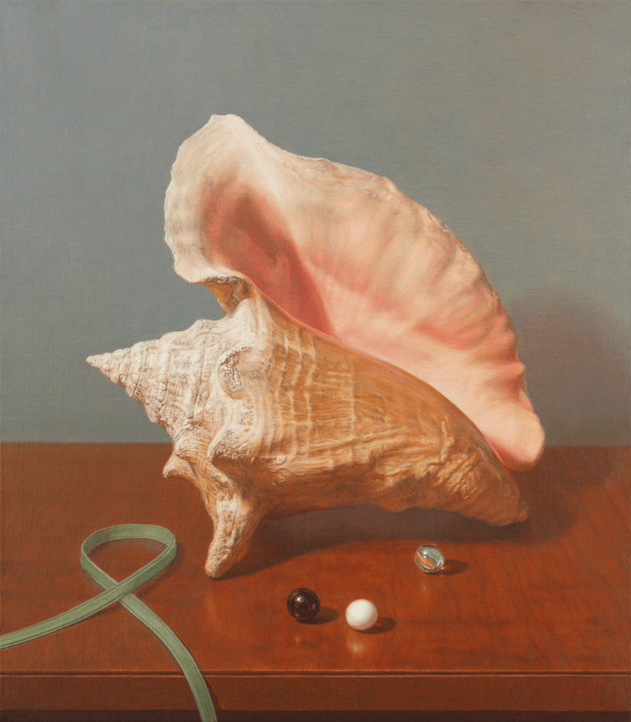 A realist oil painting on linen titled 'Conch Shell,' measuring 16 inches by 14 inches. A large, cream-coloured conch shell with a smooth, pale pink interior rests on a highly reflective wooden table. In front of the shell are three small glass marbles—one black, one white, and one with a blue swirl. There is a thin, vibrant green ribbon that curls delicately across the surface and edge of the table. The polished tabletop shows a clear reflection of the shell’s pink opening, the marbles, and the green ribbon. The background is a soft, neutral grey with directional lighting from the left. Oil painting by John Hansen.