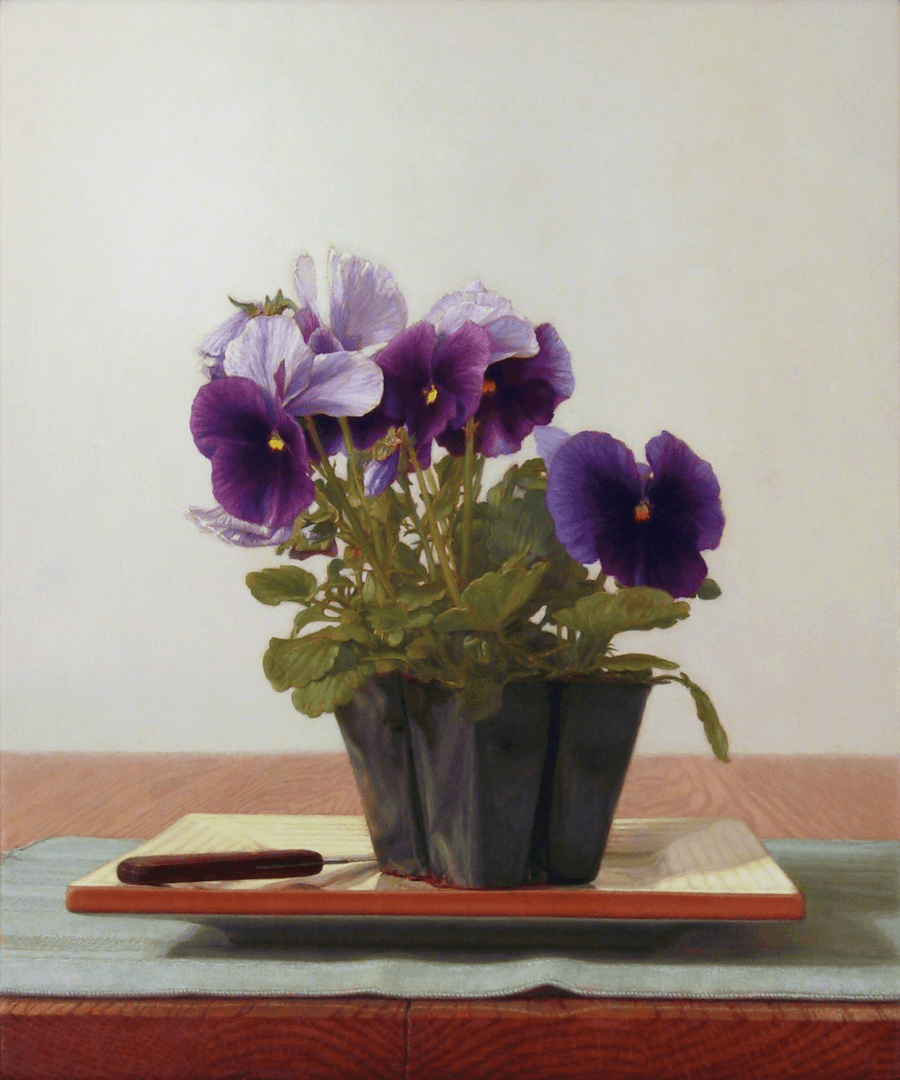 A realist still life oil painting on panel titled 'Pansies,' measuring 12 inches by 10 inches. Sitting atop of a square yellow glazed clay plate a small, plastic container holds a vibrant bunch of purple and white pansies with green leaves, and a small paring knife. The dish rests on a green place-mat atop a golden, grained oak table. Soft, directional light from the left creates delicate cast shadows and highlights the velvety texture of the flower petals against a light neutral, warm-grey background. Oil painting by John Hansen.